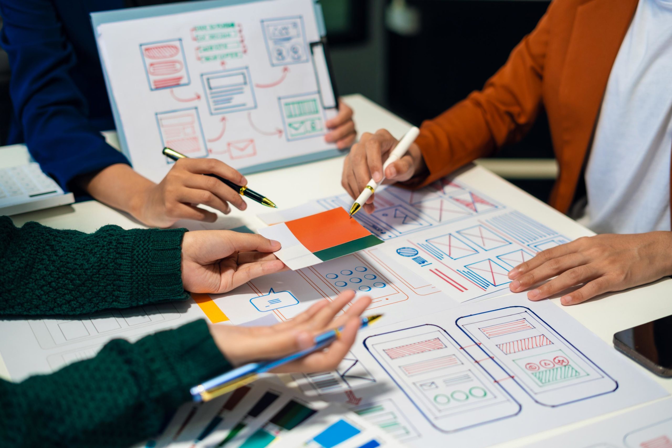 Equipo de profesionales colaborando en el diseño de interfaces digitales, trabajando sobre maquetas y prototipos de sitios web y aplicaciones móviles.